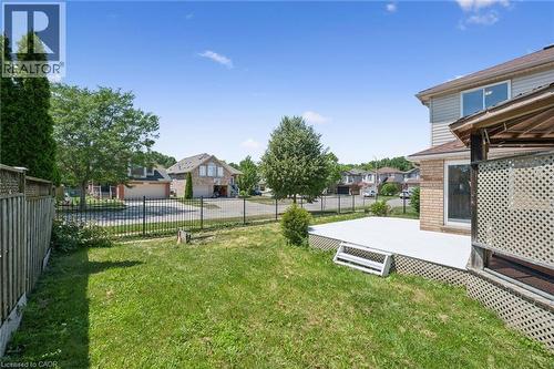 Spacious backyard featuring a manicured lawn, a large deck with lattice skirting, and a wooden fence - 71 Peach Blossom Crescent, Kitchener, ON 