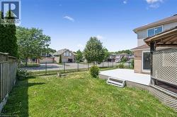 Spacious backyard featuring a manicured lawn, a large deck with lattice skirting, and a wooden fence - 