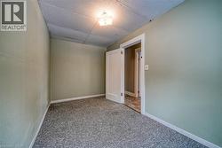 Carpeted empty room with a drop ceiling and baseboards - 