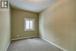 Carpeted spare room featuring a drop ceiling and baseboards - 