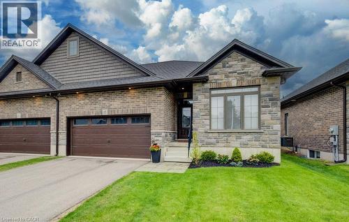 Exterior featuring a blend of brick and stone masonry, dark shingled roof, and an attached two-car garage with brown doors - 15 Matheson Crescent, Innerkip, ON - Outdoor With Facade