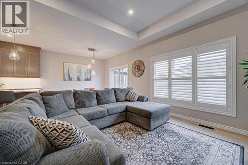 Open-concept living space featuring a tray ceiling with recessed lighting, light wood-finish flooring, and white plantation shutters - 15 Matheson Crescent, Innerkip, ON - Indoor Photo Showing Living Room