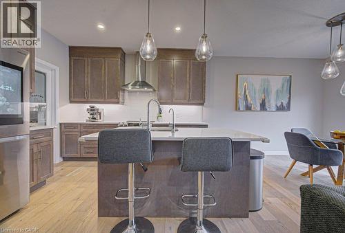 Kitchen featuring wood-finish cabinetry, stainless steel appliances, a center island with countertop seating, and light wood-finish flooring - 15 Matheson Crescent, Innerkip, ON - Indoor