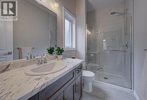 Bathroom featuring a glass-enclosed shower with tile surround, a single vanity with a marble-patterned countertop, and a large mirror - 15 Matheson Crescent, Innerkip, ON - Indoor Photo Showing Bathroom