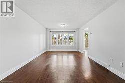 Bright interior space featuring wood-finish flooring, white baseboards, and light gray walls - 
