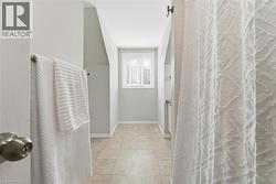 Bathroom featuring tiled flooring, light gray walls, a window with blinds, and white trim - 
