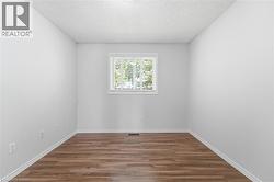 Room featuring wood-finish flooring, white walls, and a window with horizontal blinds - 