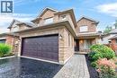 Brick and stone exterior featuring a two-car garage, paved driveway, and covered front porch - 43 Liam Drive, Ancaster, ON  - Outdoor 