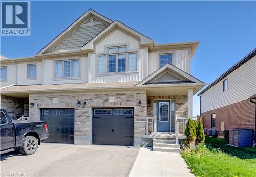 Modern townhouse exterior featuring light-colored vertical siding and stone veneer accents - 80 Miranda Path, Elmira, ON - Outdoor With Facade