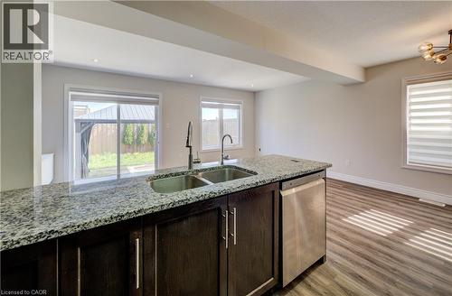 Kitchen island featuring a dual stainless steel sink, a stainless steel dishwasher, and a speckled countertop - 80 Miranda Path, Elmira, ON - Indoor Photo Showing Kitchen With Double Sink