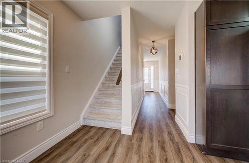 Foyer featuring wood-finish flooring, wainscoting, a carpeted staircase, and a contemporary ceiling light fixture - 80 Miranda Path, Elmira, ON - Indoor Photo Showing Other Room