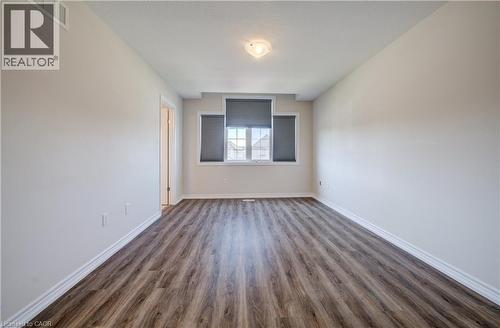 Spacious room featuring wood-finish flooring, light-colored walls, white baseboards, and a window with blinds - 80 Miranda Path, Elmira, ON - Indoor Photo Showing Other Room