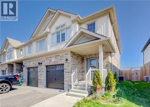 Modern townhome featuring a stone and siding exterior, a covered front entry, and a two-car driveway leading to two separate garage doors - 80 Miranda Path, Elmira, ON - Outdoor