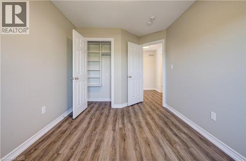 Interior room featuring wood-finish flooring, light-toned wall paint, white baseboards, and a built-in closet with shelving - 80 Miranda Path, Elmira, ON - Indoor Photo Showing Other Room