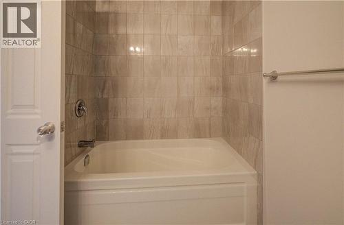 White bathtub with chrome fixtures and light-toned, vertically oriented wall tiling - 80 Miranda Path, Elmira, ON - Indoor Photo Showing Bathroom