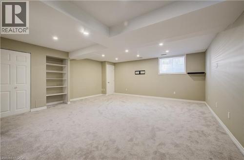 Spacious room featuring light gray carpeting, recessed ceiling lighting, a built-in shelving unit, and a window with blinds - 80 Miranda Path, Elmira, ON - Indoor Photo Showing Basement