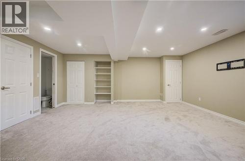 Spacious room featuring light-colored carpet, recessed ceiling lighting, built-in shelving, and multiple white panel doors - 80 Miranda Path, Elmira, ON - Indoor Photo Showing Basement