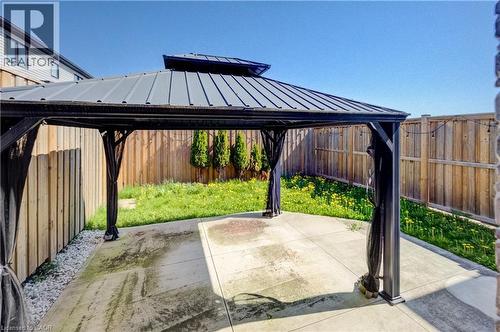 Backyard gazebo with a metal roof and privacy screens, featuring a concrete patio, a green lawn, and wood fencing - 80 Miranda Path, Elmira, ON - Outdoor