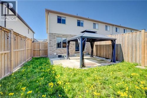 Backyard patio featuring a dark metal gazebo, privacy fencing, and a grass area - 80 Miranda Path, Elmira, ON - Outdoor With Exterior