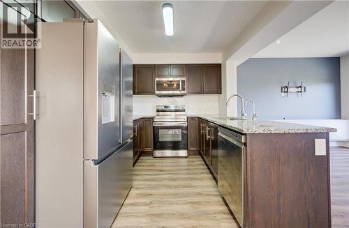 Kitchen featuring stainless steel appliances, dark wood-finish cabinetry, granite countertops, a double basin sink, and wood-finish flooring - 80 Miranda Path, Elmira, ON - Indoor Photo Showing Kitchen With Upgraded Kitchen