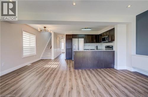 Open-concept living space featuring wood-finish flooring, a contemporary kitchen with dark cabinetry, stainless steel appliances, a breakfast bar, and recessed lighting - 80 Miranda Path, Elmira, ON - Indoor Photo Showing Kitchen