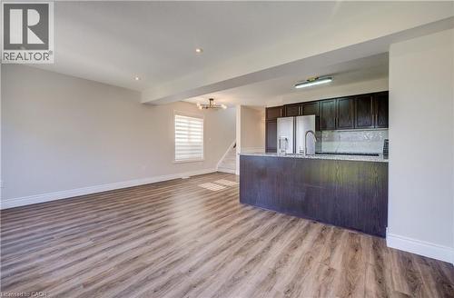 Open-concept living area featuring wood-finish flooring, recessed lighting, and a window with horizontal blinds - 80 Miranda Path, Elmira, ON - Indoor Photo Showing Kitchen