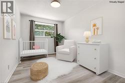 Interior room with light wood-finish flooring, white walls, and a window with exterior tree views - 
