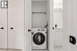 Dedicated laundry closet featuring a front-load washer, overhead hanging rod, and bifold doors - 