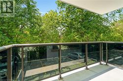 Outdoor balcony featuring clear glass panel railing with metal posts and top rail, concrete flooring, and an overhead white ceiling panel - 