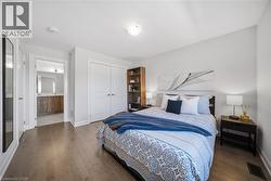 Bedroom with a closet, dark wood-style floors, and ensuite bathroom - 