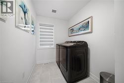 Laundry room with washing machine and dryer and light tile patterned floors - 