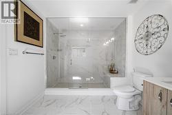 Bathroom with vanity, a marble finish shower, and light marble finish floors - 