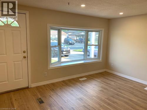 Bright interior space featuring a prominent bay window with white trim, wood-finish flooring, recessed lighting, and a white paneled entry door with an arched transom - 86 Belwood Crescent, Kitchener, ON - Indoor Photo Showing Other Room