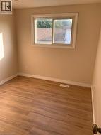 Interior room featuring wood-finish flooring, neutral wall paint, and white baseboards - 