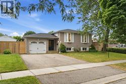 Brick exterior residence featuring a single-car garage with a white door, bay windows with shutters, mature front yard landscaping, and a paved driveway - 