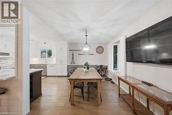 Open-concept dining area featuring wood-finish flooring, a contemporary pendant light fixture, and white window shutters - 