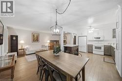 Open-concept living and kitchen area featuring wood-finish flooring, white walls, and crown molding - 