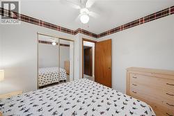 Bedroom featuring a ceiling fan with light fixture, mirrored sliding closet doors, and a wood-paneled door - 