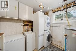 Dedicated utility room featuring overhead cabinetry, wall paneling, a utility sink, and a window - 