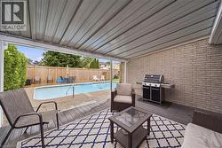 Covered patio featuring a ribbed metal ceiling, wood-finish flooring, and a light-toned brick wall - 