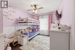 Bedroom with vaulted ceiling, wood-finish flooring, and wainscoting - 