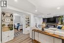 Open concept living space featuring wood-finish flooring, a built-in electric fireplace with a stone surround, and an accent wall with shiplap paneling - 120 Elgin Crescent, Waterloo, ON  - Indoor With Fireplace 
