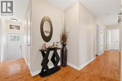 Hallway with wood-finish flooring, light neutral wall color, white baseboards, and multiple doorways - 