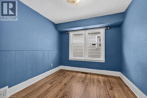 Room featuring wood-finish flooring, two-pane window with white trim, and a white ceiling - 23 Harrison Avenue, Hamilton, ON - Indoor Photo Showing Other Room