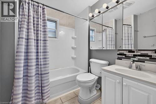 Full bathroom featuring a white vanity with integrated sink, chrome faucet, and mirrored medicine cabinet - 23 Harrison Avenue, Hamilton, ON - Indoor Photo Showing Bathroom