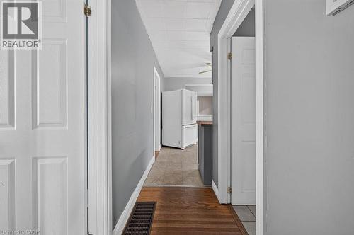 Hallway with gray wall paint and wood-finish flooring extending into a tiled area - 23 Harrison Avenue, Hamilton, ON - Indoor Photo Showing Other Room