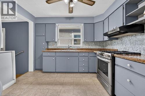 Kitchen featuring blue cabinetry, a stainless steel range, and a ceiling fan - 23 Harrison Avenue, Hamilton, ON - Indoor Photo Showing Kitchen With Double Sink