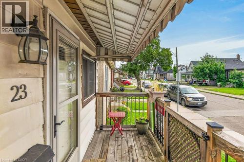 Front porch with wood decking, lattice railing, and an overhead awning - 23 Harrison Avenue, Hamilton, ON - Outdoor With Exterior