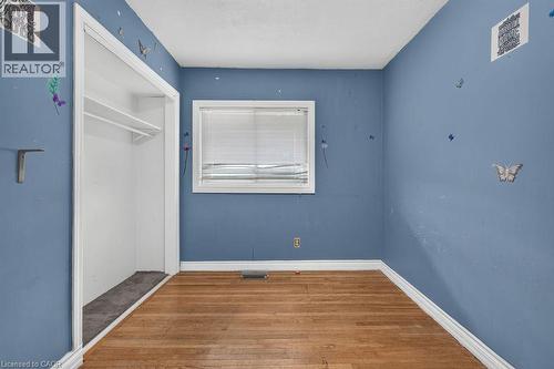 Room featuring wood-finish flooring, a window with blinds, and an open closet with shelving - 23 Harrison Avenue, Hamilton, ON - Indoor Photo Showing Other Room