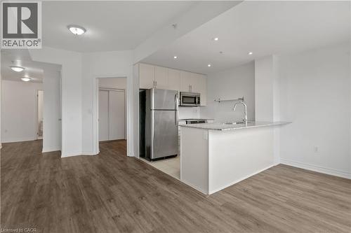 Open-concept living space featuring wood-finish flooring, a kitchen island with seating, stainless steel appliances, white cabinetry, and recessed lighting - 427 Aberdeen Avenue Unit# 102, Hamilton, ON - Indoor Photo Showing Kitchen